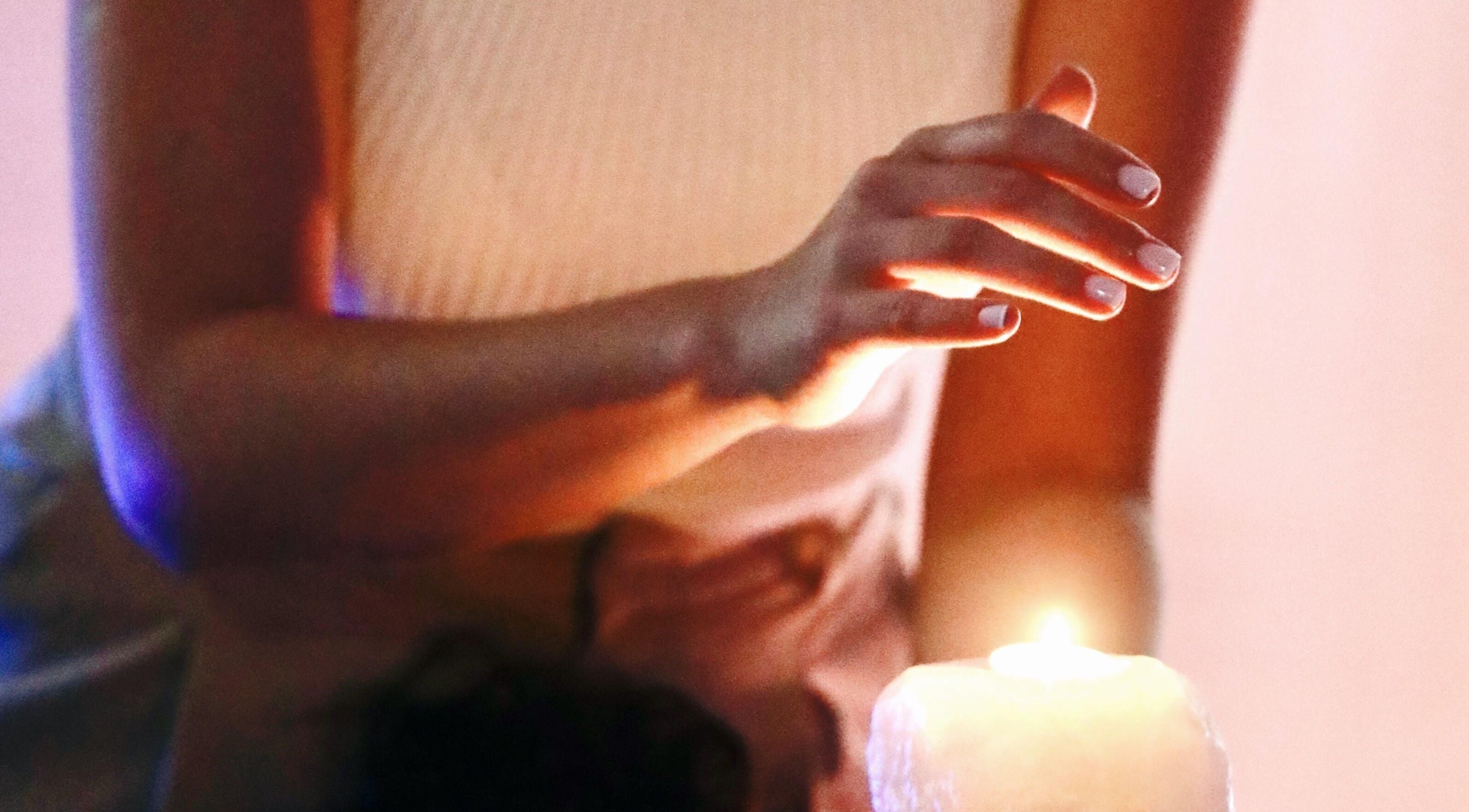 Hand gracefully hovering over a lit candle at Con Calma, Elda, Comunidad Valenciana, ES. Tranquil ambiance.