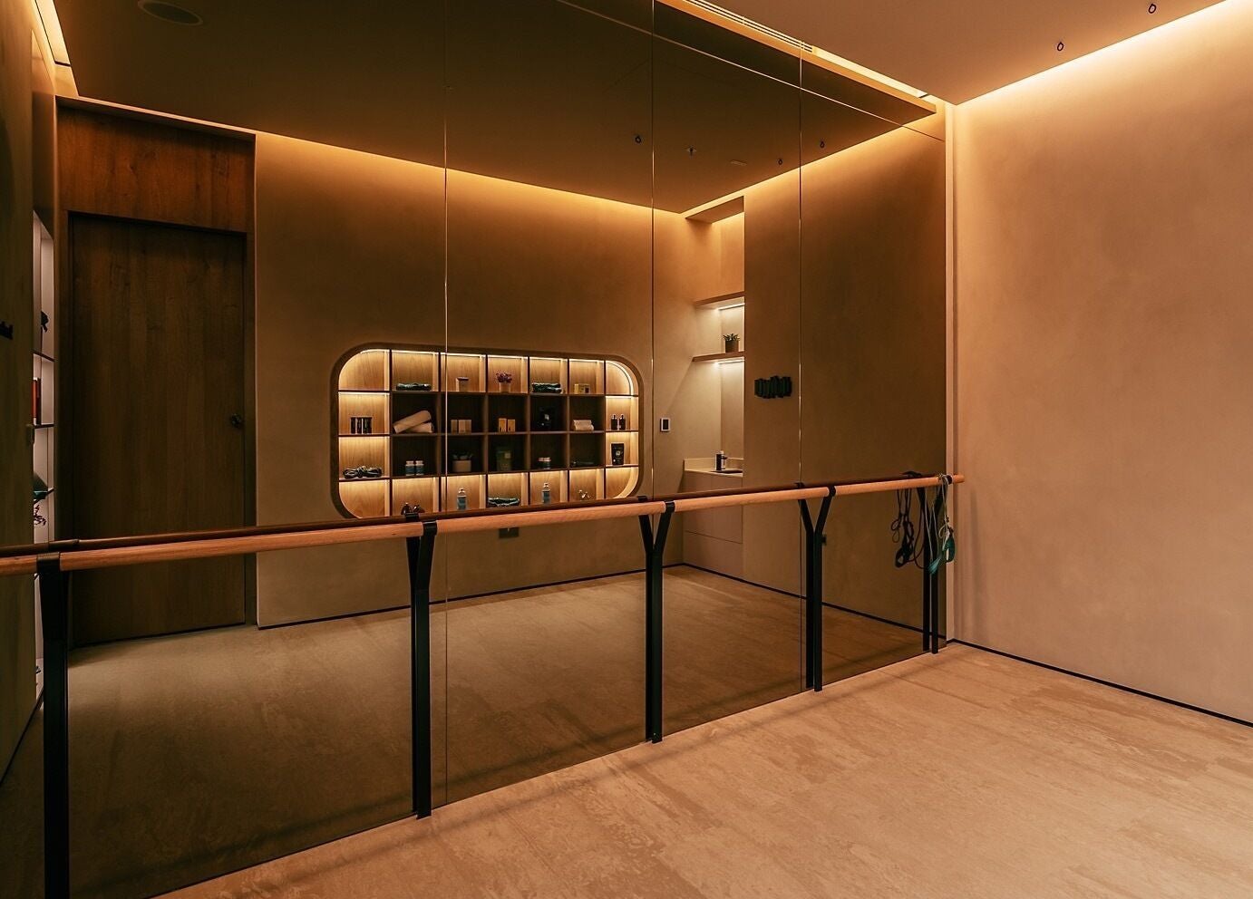 Sleek interior of Wellnest's fitness studio in Dubai, AE, featuring warm lighting and mirrored walls.