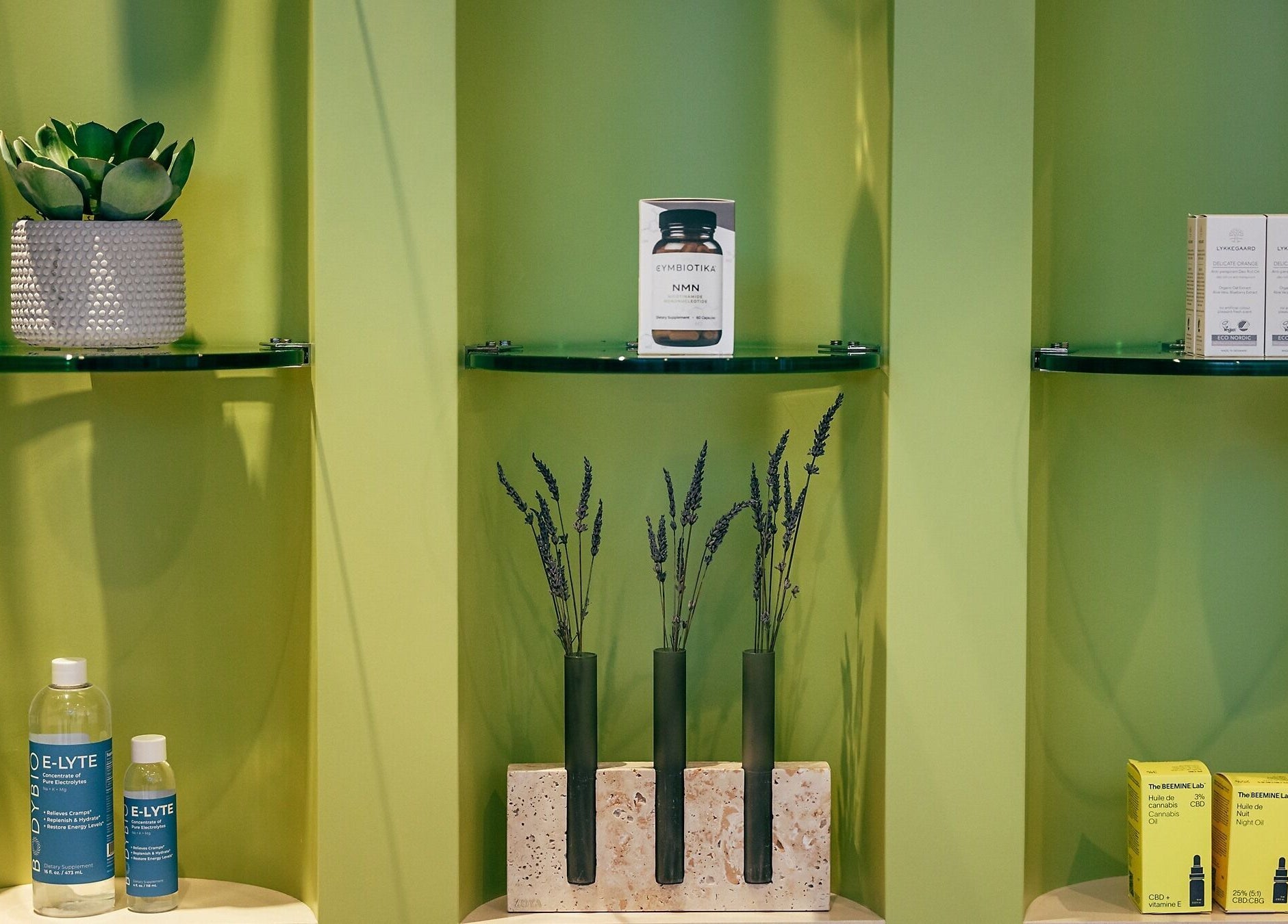 Elegant product display at Wellnest, Dubai, AE with wellness items on green shelves.