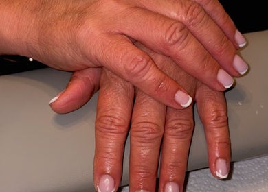 Elegant French manicure by Mobile nails by Karli in Stilton, England, GB. Perfectly polished hands resting on a cushion.