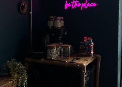 Chic neon-lit interior at Sacred Hair, North Shields, England. Aesthetic wooden counter with jars and decor.