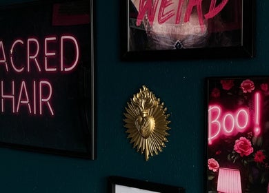 Neon sign at Sacred Hair, North Shields, England, GB with artistic decor on a dark wall.