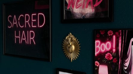 Neon sign at Sacred Hair, North Shields, England, GB with artistic decor on a dark wall.