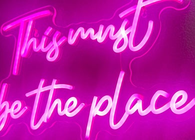 Neon sign at Sacred Hair, North Shields, England, GB. Vibrant pink text creating a welcoming ambiance.