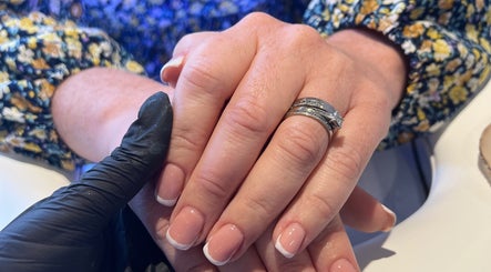 Elegant French manicure at Beauty By Chloe in Leeds, England, GB. Hand with silver rings subtly displayed.