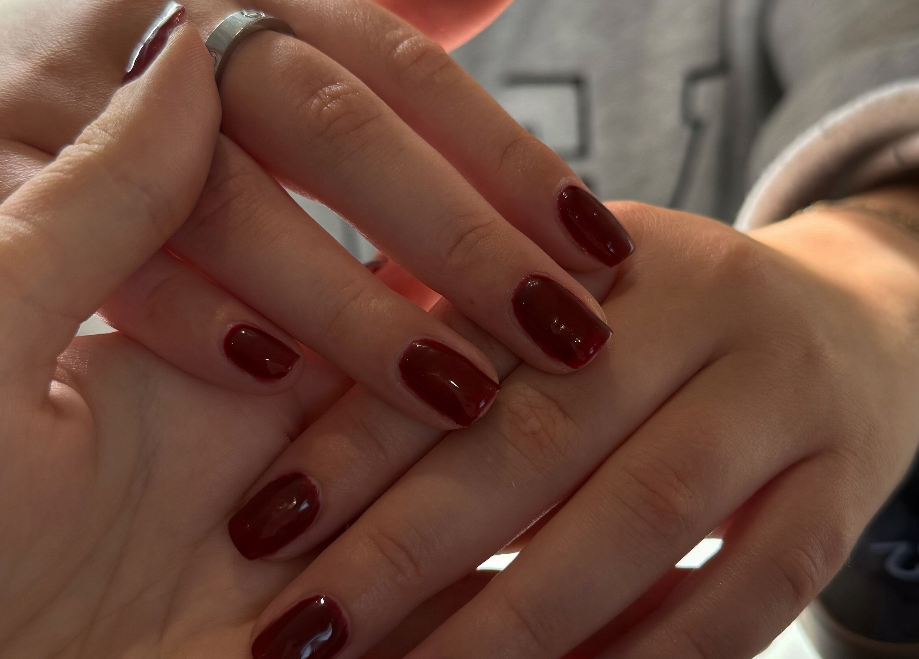 Close-up of freshly painted nails at Beauty By Chloe, Leeds, England, GB, featuring a rich burgundy color.