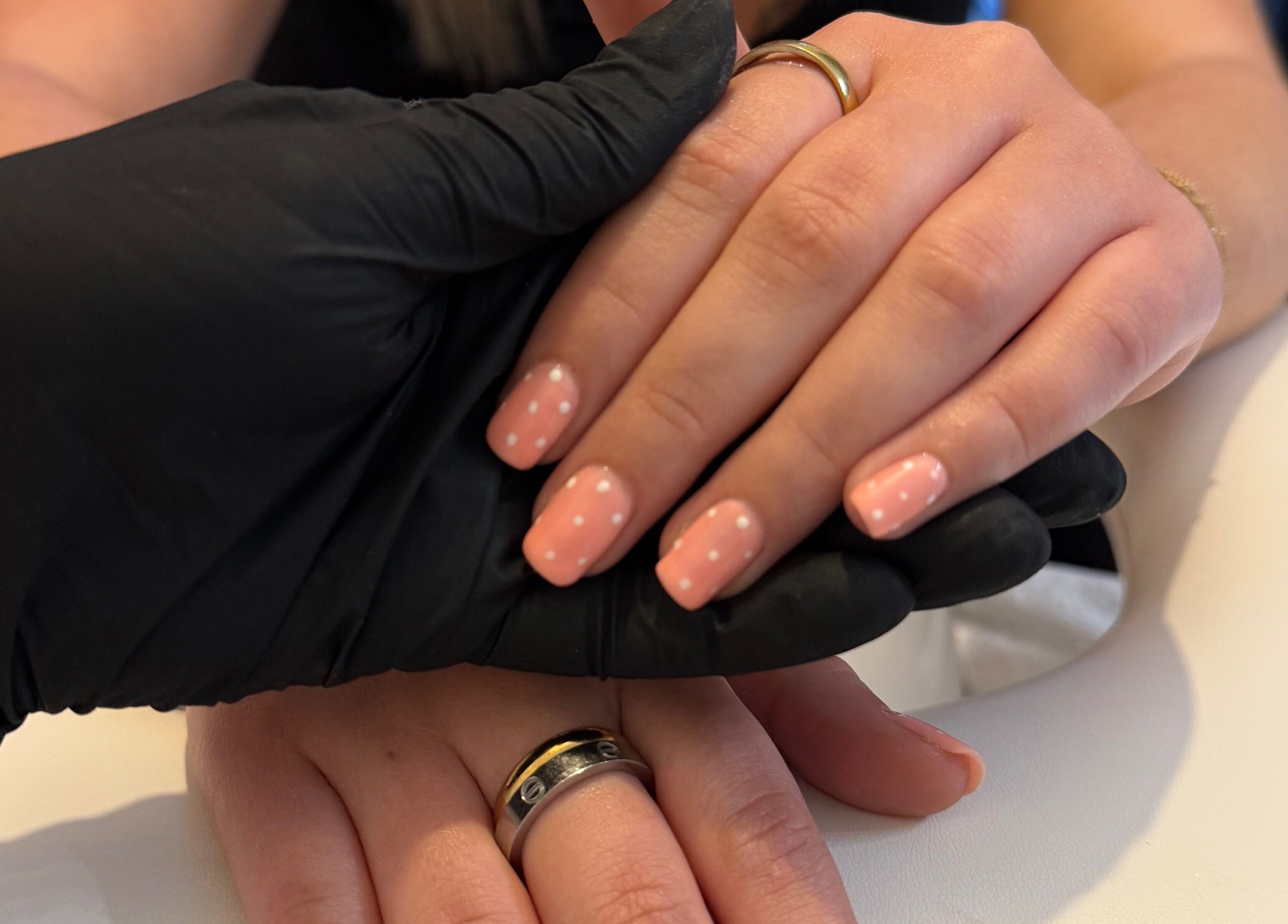 Polka dot nail art at Beauty By Chloe, Leeds, England, GB. Hands with pink nails held by stylist.