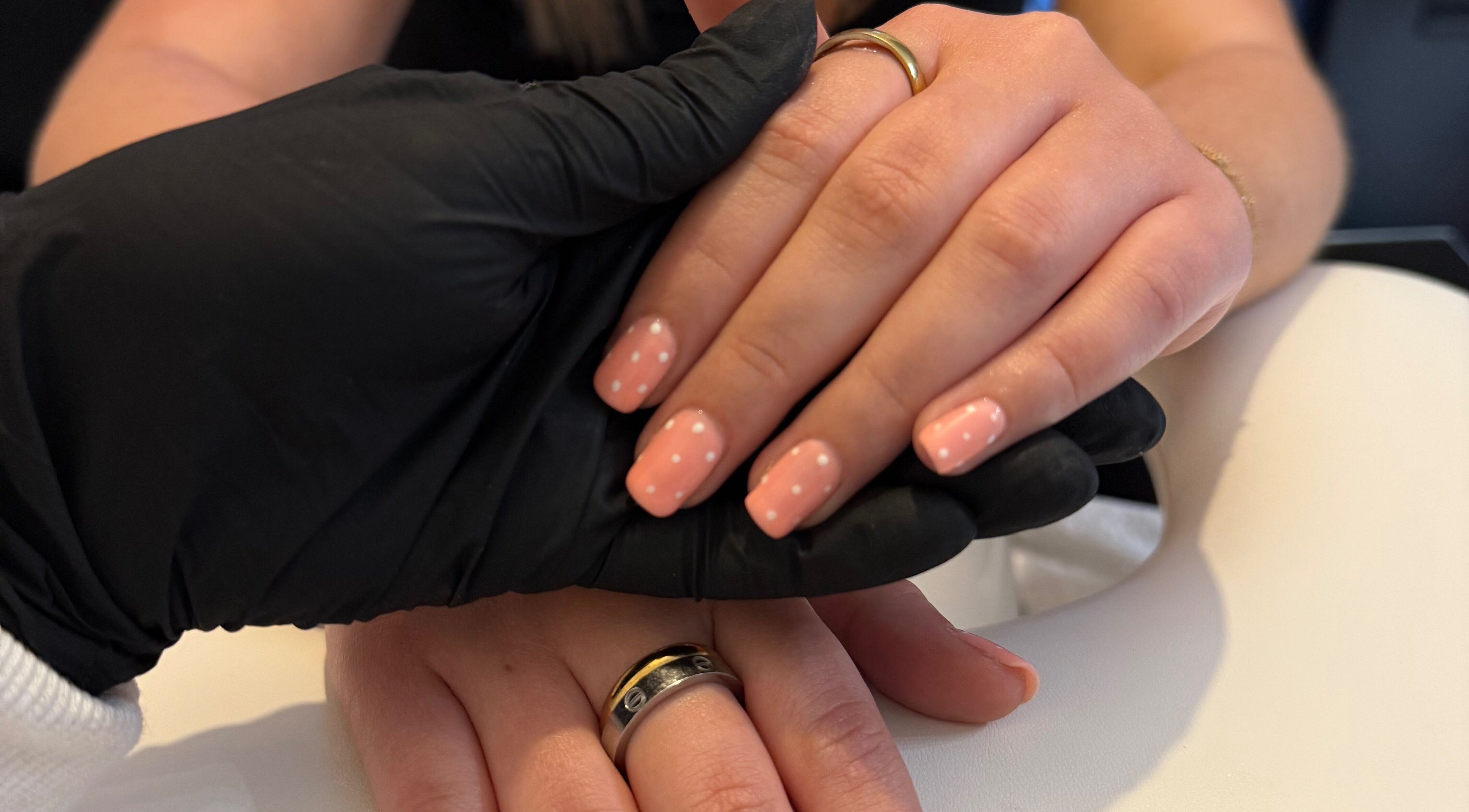 Polka dot nail art at Beauty By Chloe, Leeds, England, GB. Hands with pink nails held by stylist.
