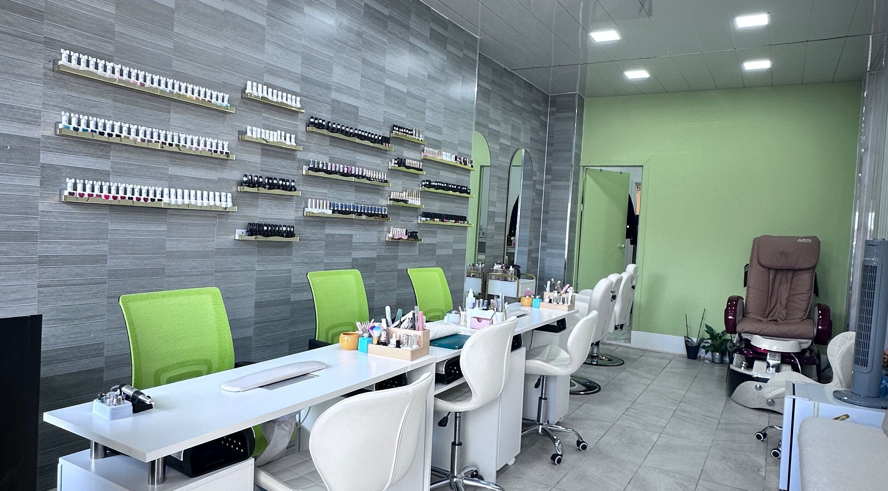 Modern manicure stations at Vivid nails&beauty in Glasgow, Scotland, GB showcasing green chairs and polish displays.