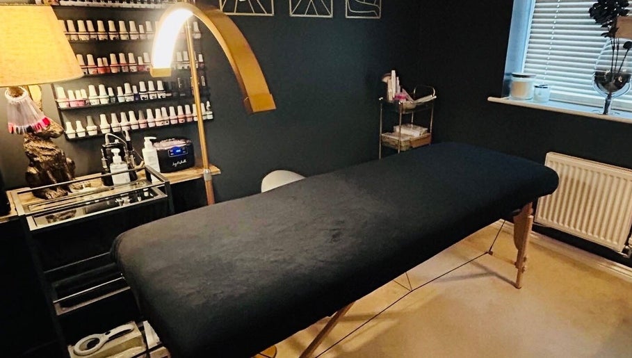 Cozy treatment room at Forever Young Beauty, Tongham, England, GB, featuring a massage table and nail polishes.