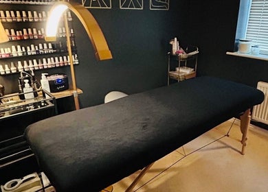 Cozy treatment room at Forever Young Beauty, Tongham, England, GB, featuring a massage table and nail polishes.