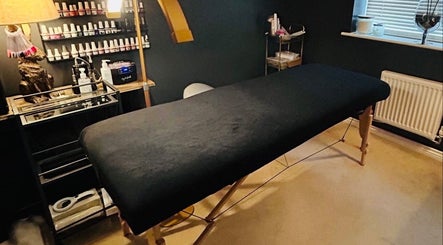 Cozy therapy room at Forever Young Beauty, Tongham, England, GB with a massage bed and nail polish display.