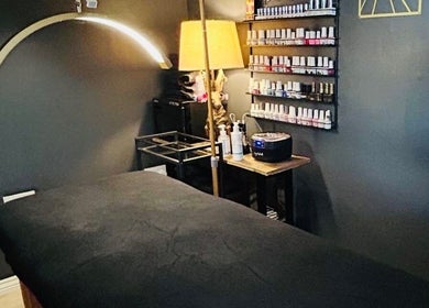 Relaxing massage room at Forever Young Beauty, Tongham, England, GB with treatment bed and nail polish display.