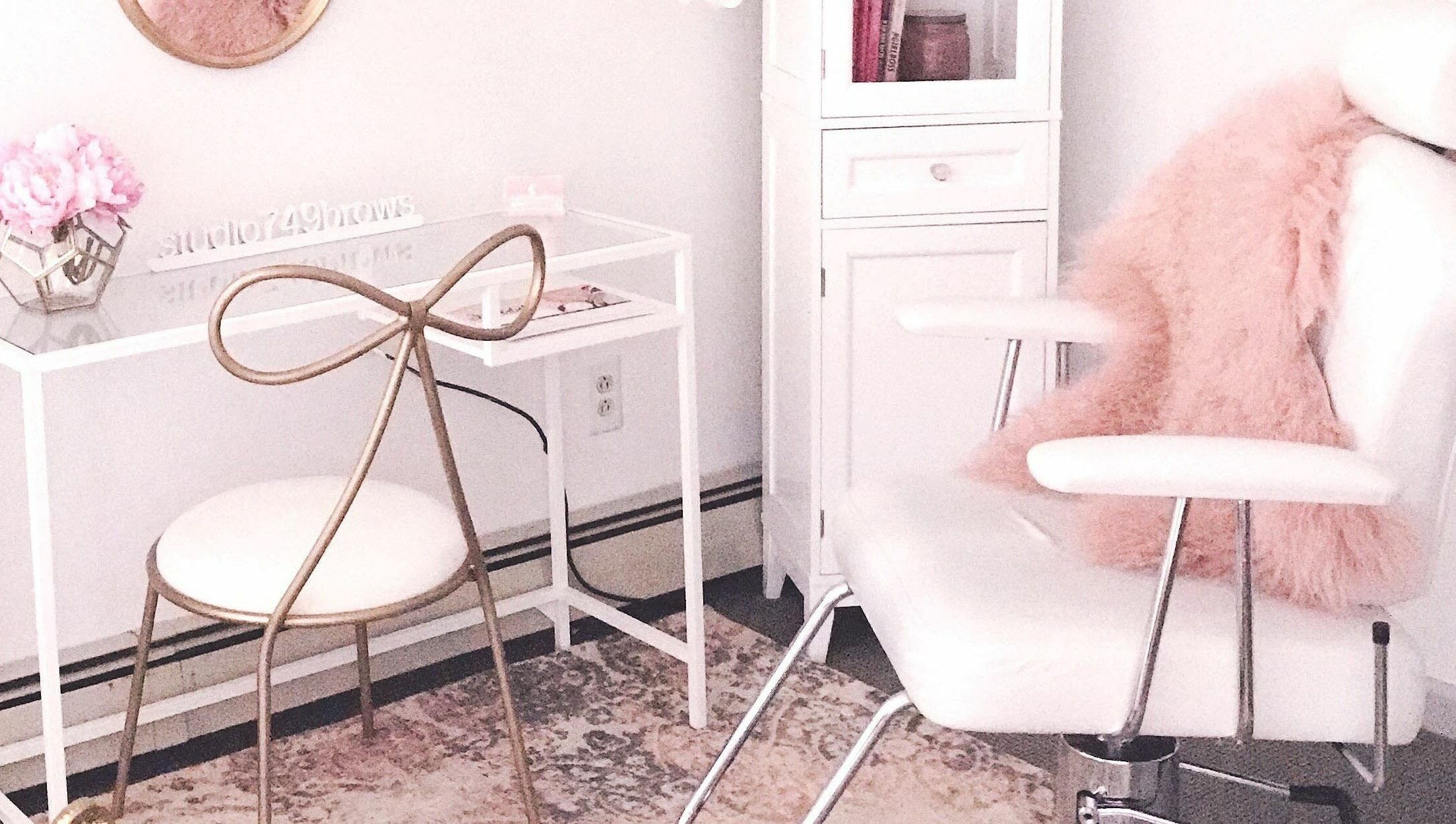 Elegant salon interior at Studio749Brows in Township of Washington, New Jersey, US. White chair with pink accents.