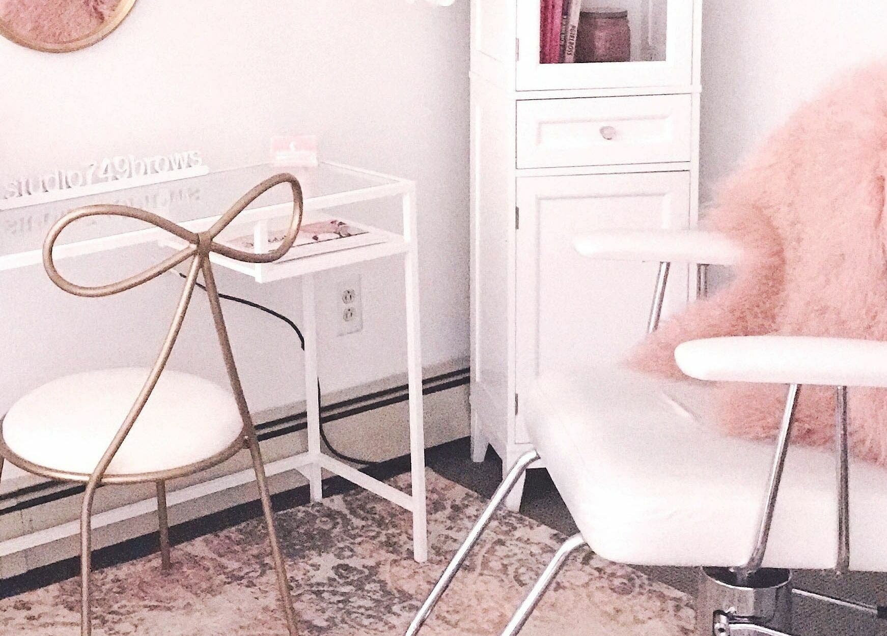 Elegant salon interior at Studio749Brows in Township of Washington, New Jersey, US. White chair with pink accents.
