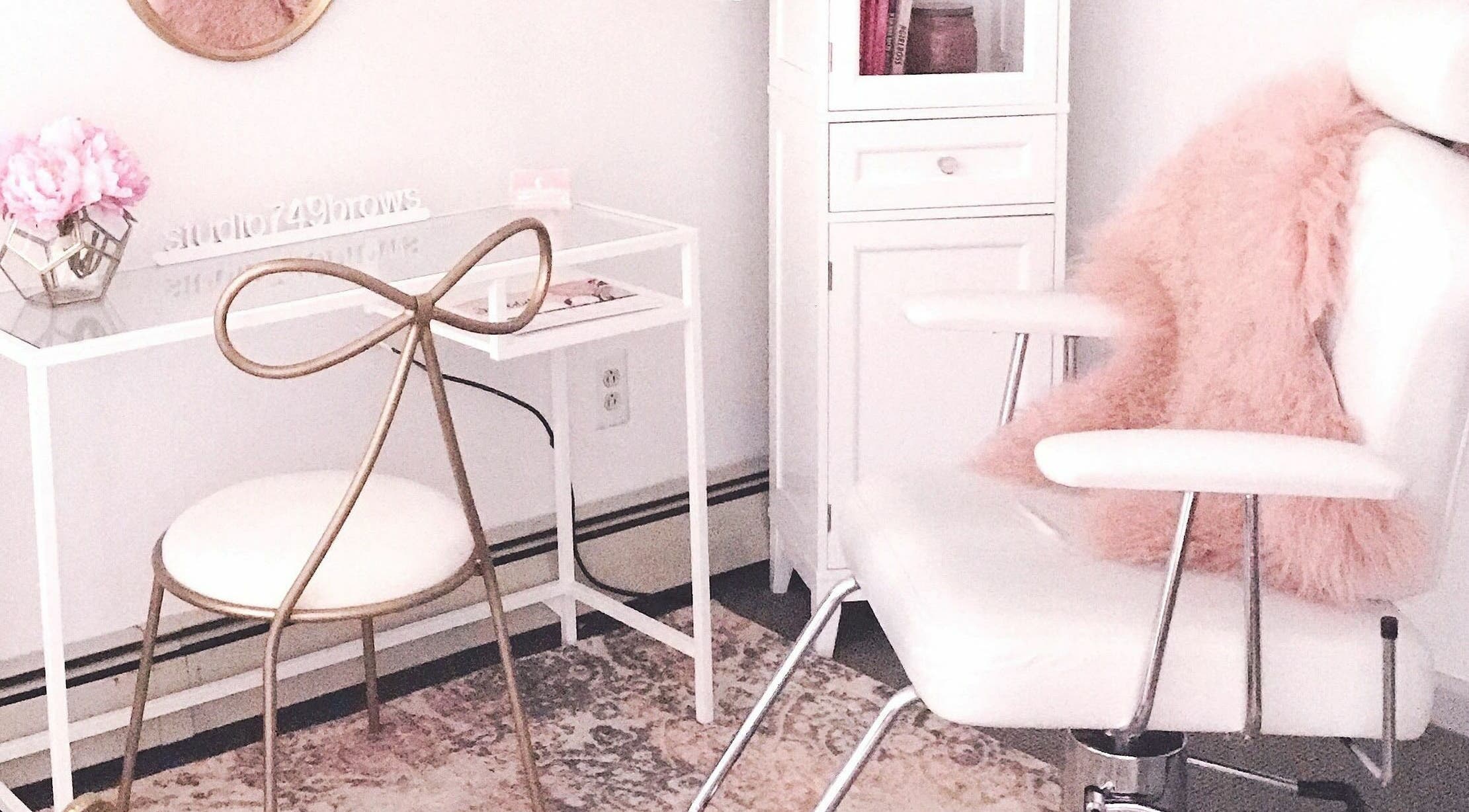 Elegant salon interior at Studio749Brows in Township of Washington, New Jersey, US. White chair with pink accents.