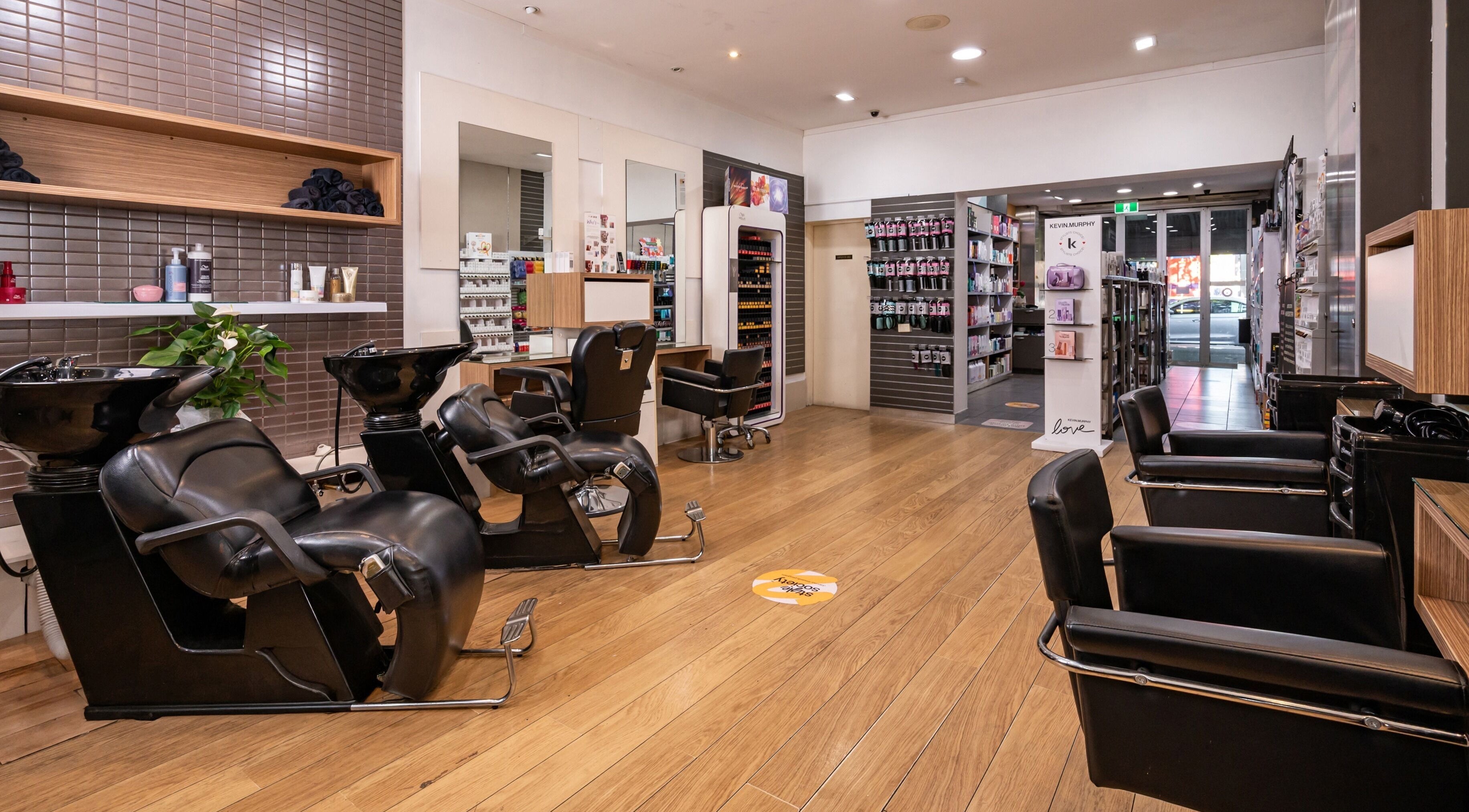 Modern salon interior at Hair Enhance Carlton, Melbourne, Victoria, AU, showcasing sleek black styling chairs.