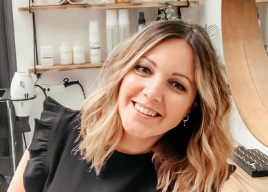 Sarah Roberts smiling in her salon, London, England, GB, showcasing hair styling station.