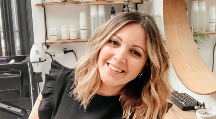 Sarah Roberts smiling in her salon, London, England, GB, showcasing hair styling station.