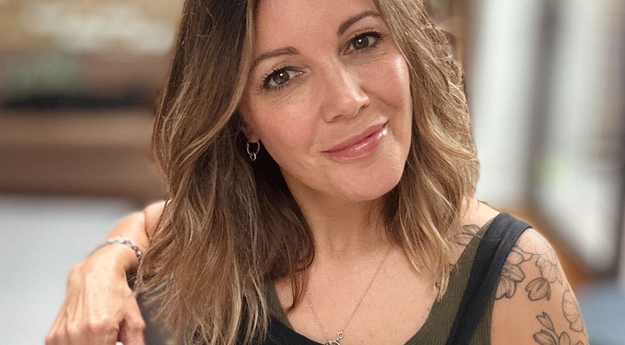 Portrait of a smiling woman with floral tattoo at Sarah Roberts, London, England, GB