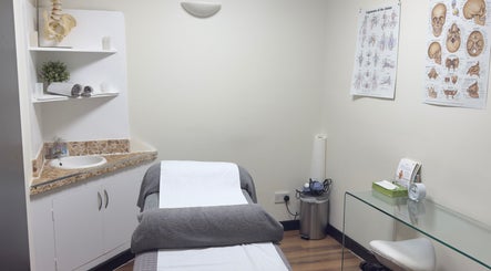 Treatment room at Mistry Osteopath South Ealing in London, England, GB with massage table and anatomical charts.