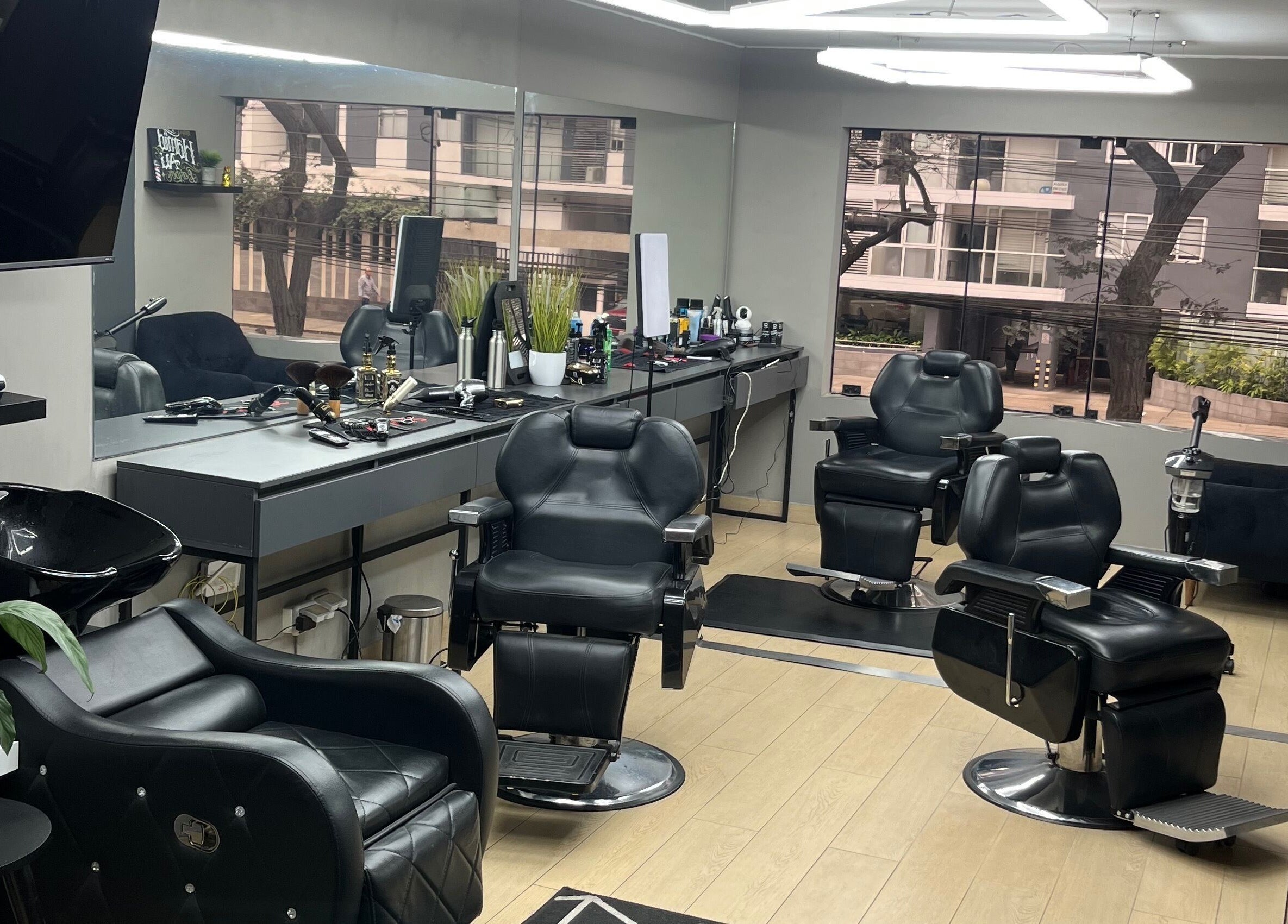 Interior moderno de Victory Barber Studio en Miraflores, Provincia De Lima, PE con sillas de peluquería negras.