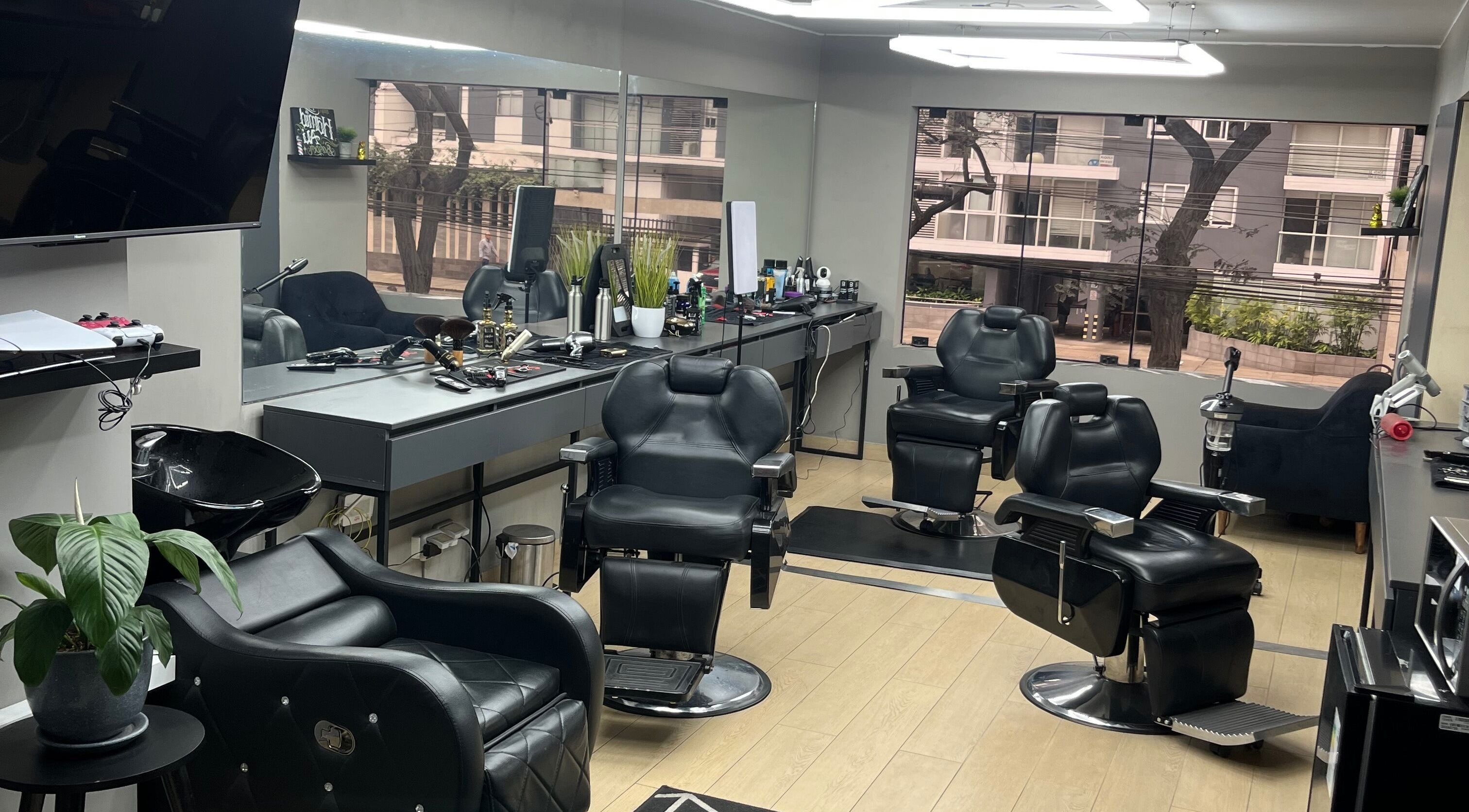 Interior moderno de Victory Barber Studio en Miraflores, Provincia De Lima, PE con sillas de peluquería negras.