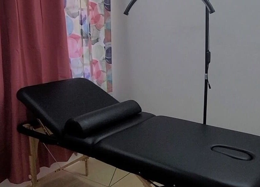 Massage table setup at Demure Aesthetics, 6729+8V Providence, Tobago, TT with floral curtains and soft lighting.