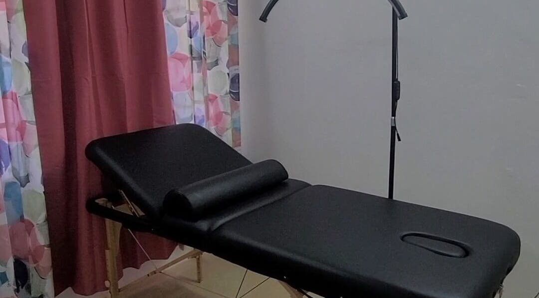 Massage table setup at Demure Aesthetics, 6729+8V Providence, Tobago, TT with floral curtains and soft lighting.