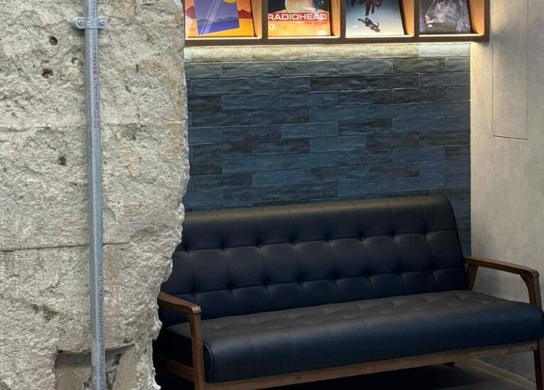 Cozy black leather sofa with textured walls at Silent Blue Barbershop, Hong Kong, HK.
