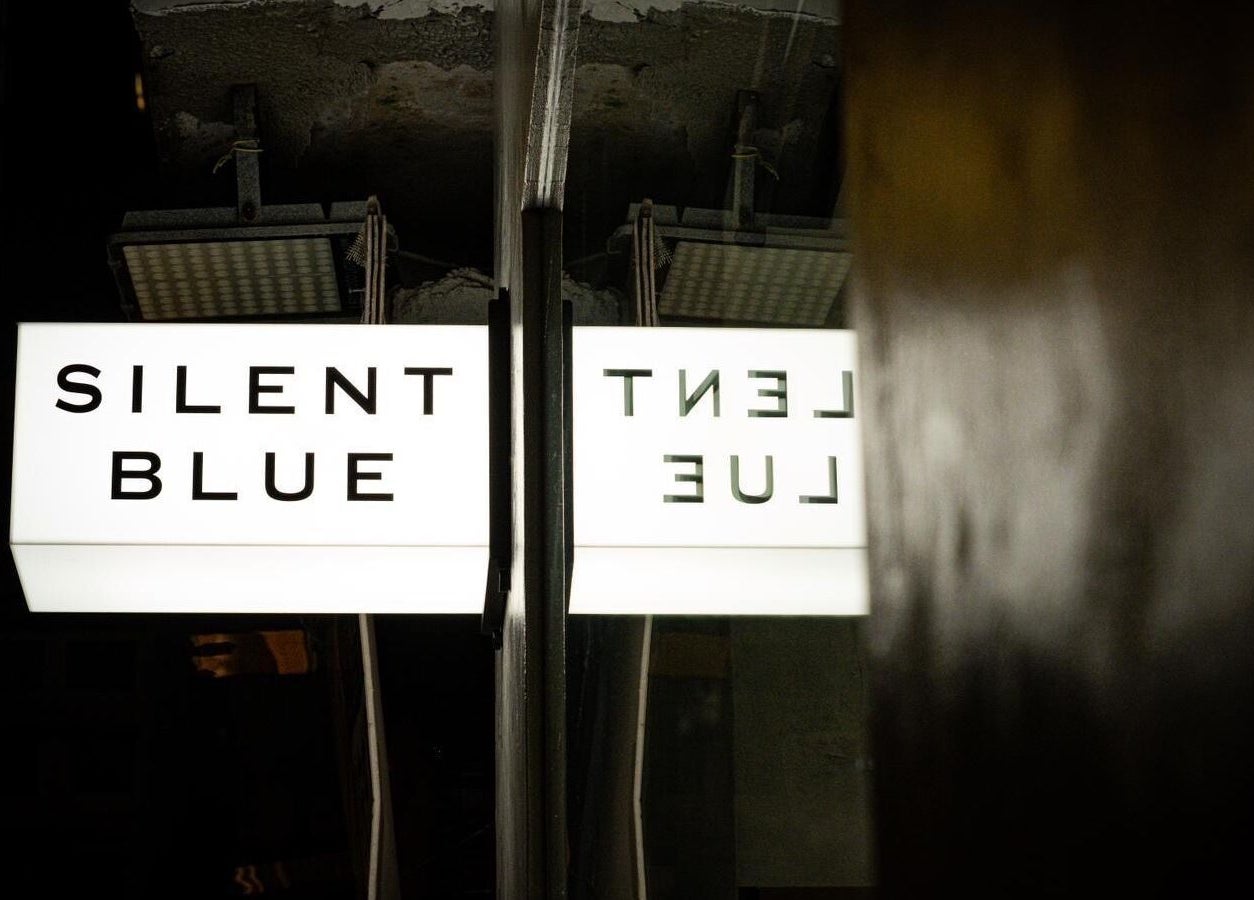 Silent Blue Barbershop glowing sign at night in Hong Kong, HK, inviting customers with its modern design.