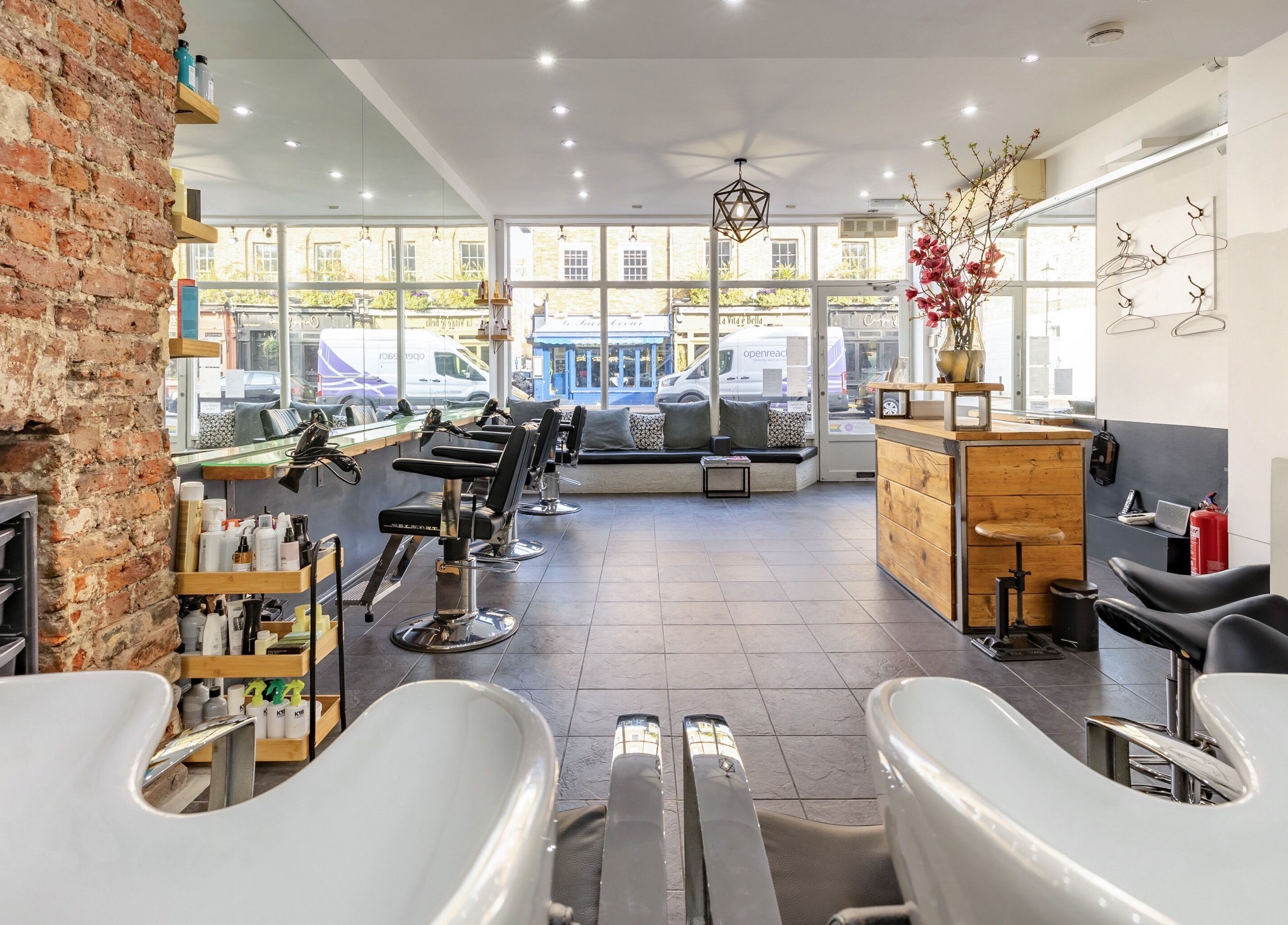 Elegant interior of Hikari Salon in London, England, GB, featuring modern chairs and exposed brick walls.