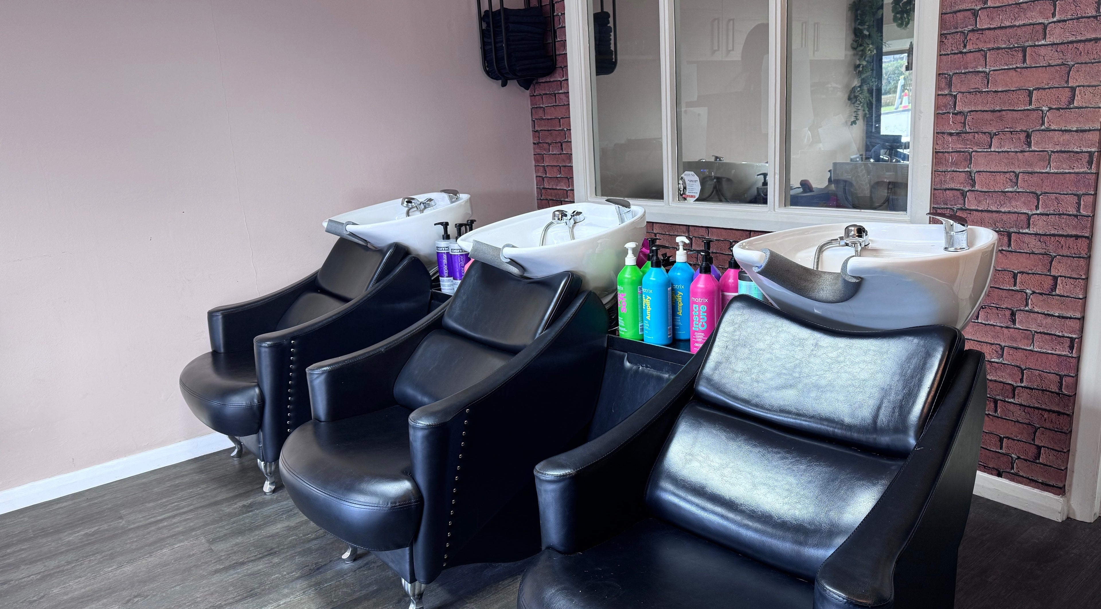 Chic hair wash stations at Hair by Emma at Xclusive, Bournemouth, England, GB, featuring modern black chairs.