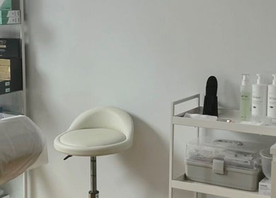 Serene corner of Kati Aesthetics in London, England, GB with a plush chair and skincare products neatly arranged.