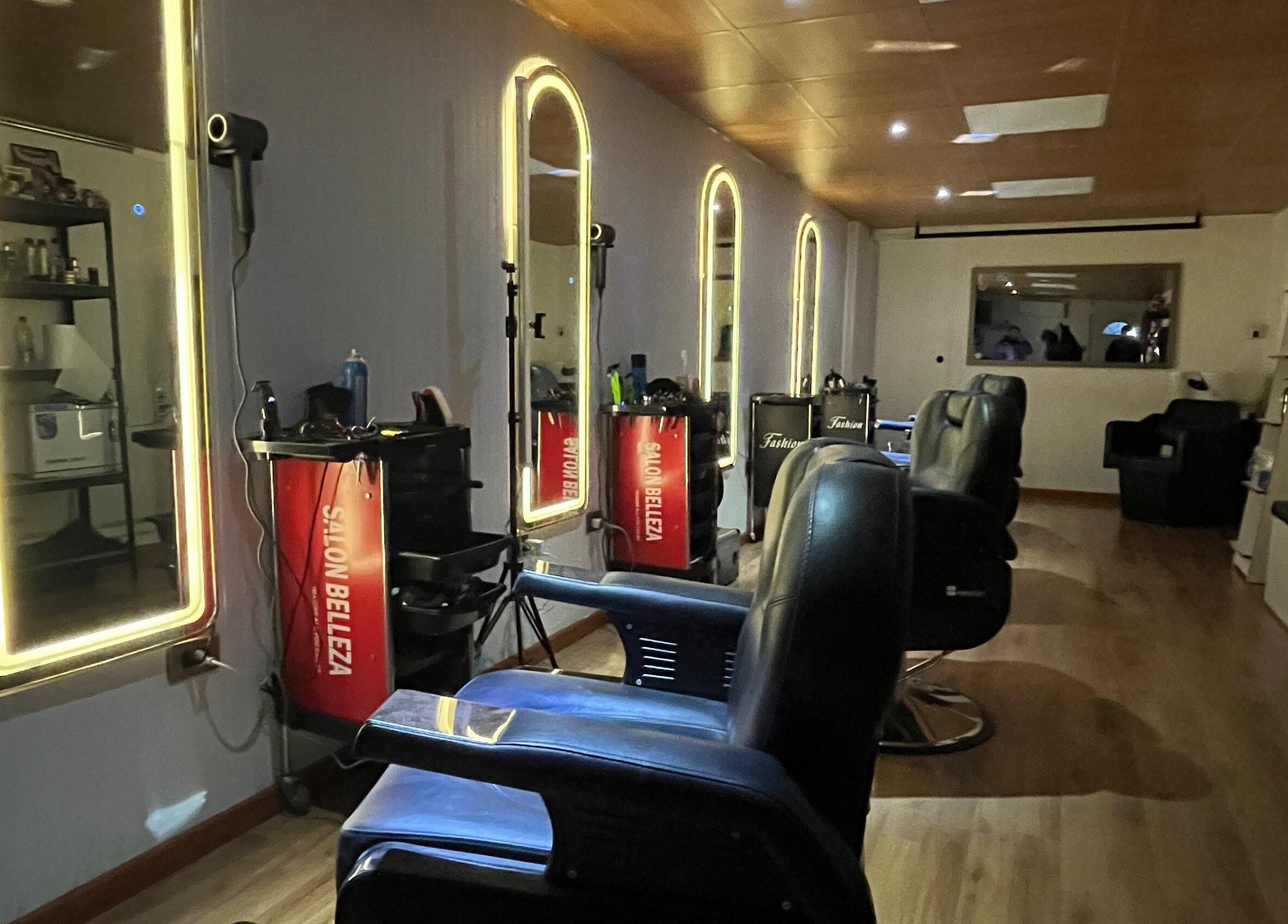 Espacio moderno en Essencial Estudio, Temuco, Araucanía, CL con espejos iluminados y sillas de barbería.