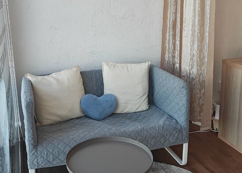 Sofá azul con cojines en Mineral Esthetic Calella, Calella, Catalunya, ES.