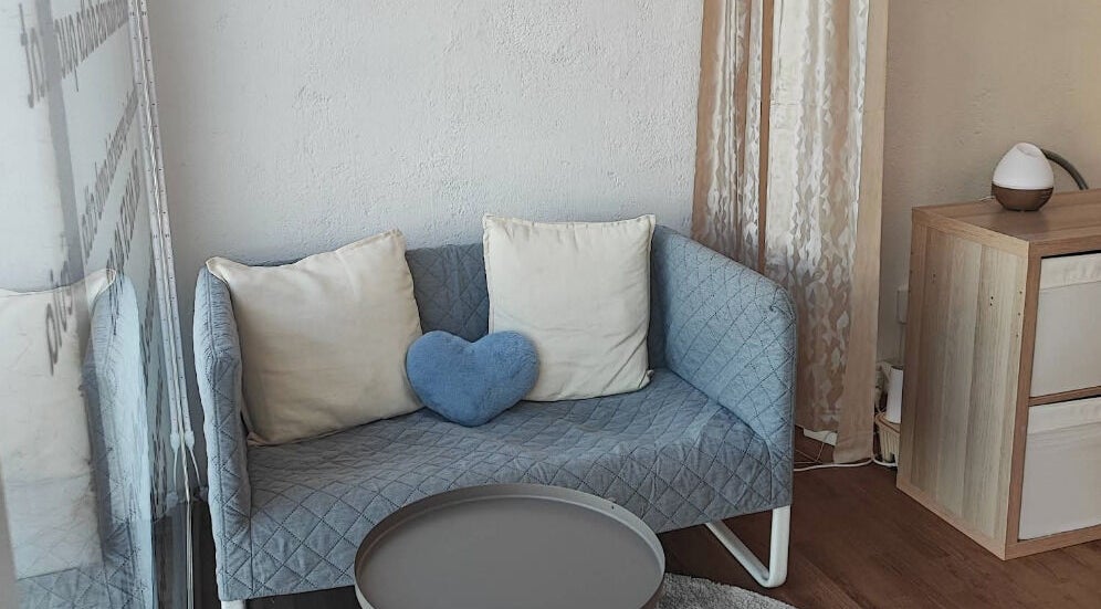 Sofá azul con cojines en Mineral Esthetic Calella, Calella, Catalunya, ES.