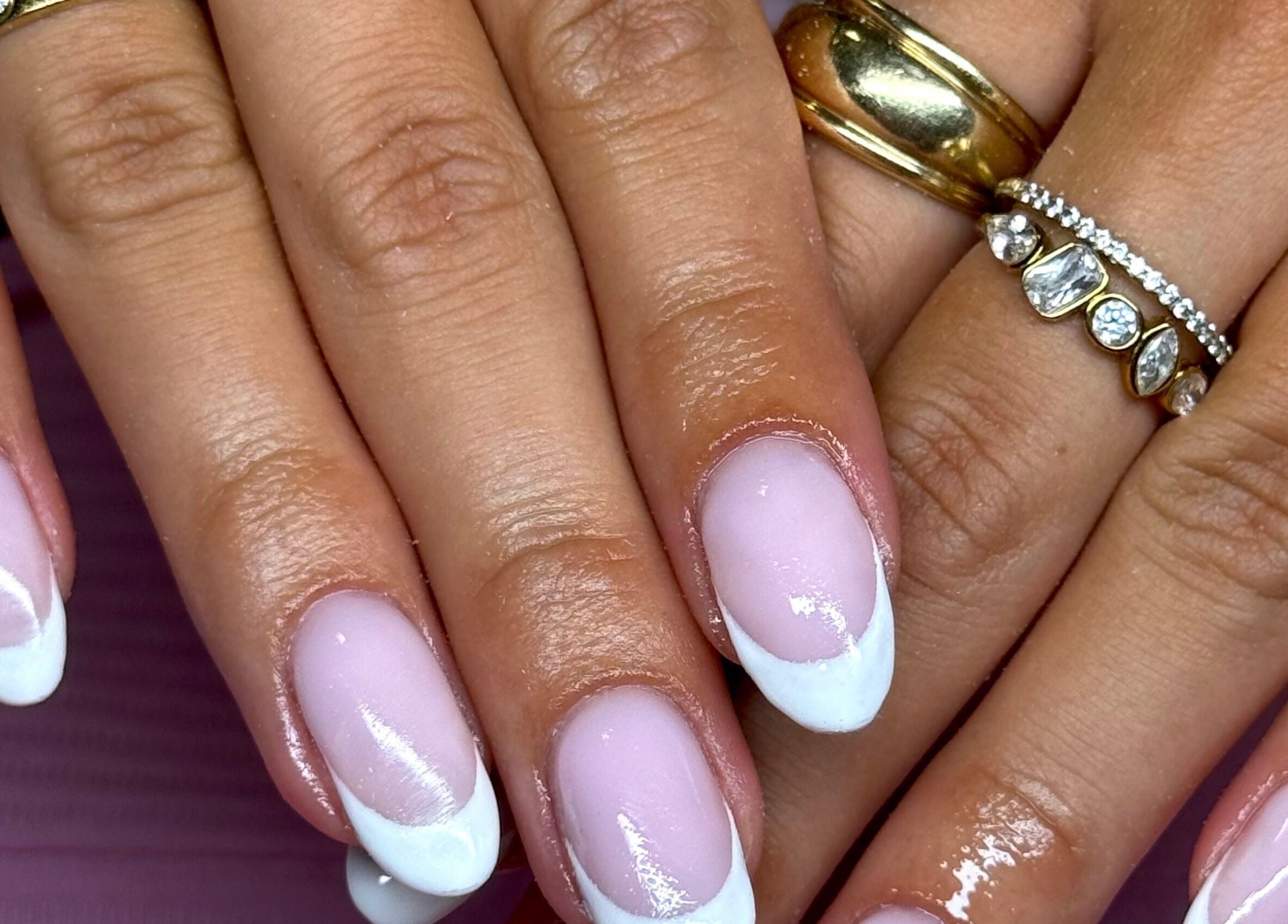 Elegant French manicure at Nails by Eden, Murrumba Downs, Queensland, AU. Gold layered rings enhance the style.