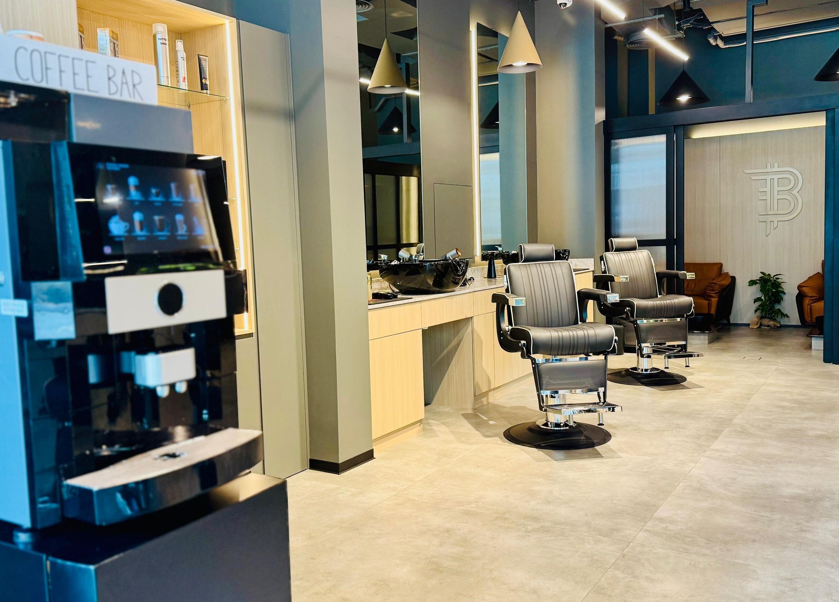 Modern interior of B27 Barbershop in Dubai, AE featuring stylish barber chairs and a sleek coffee station.