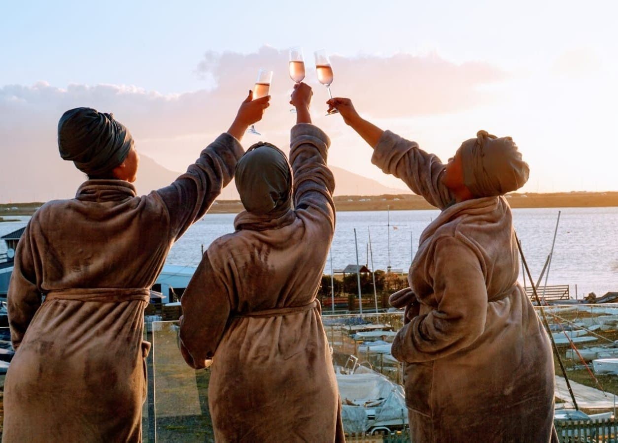 Guests enjoy a sunset toast in robes at Chalila Wellness, Cape Town, Western Cape, ZA overlooking the water.