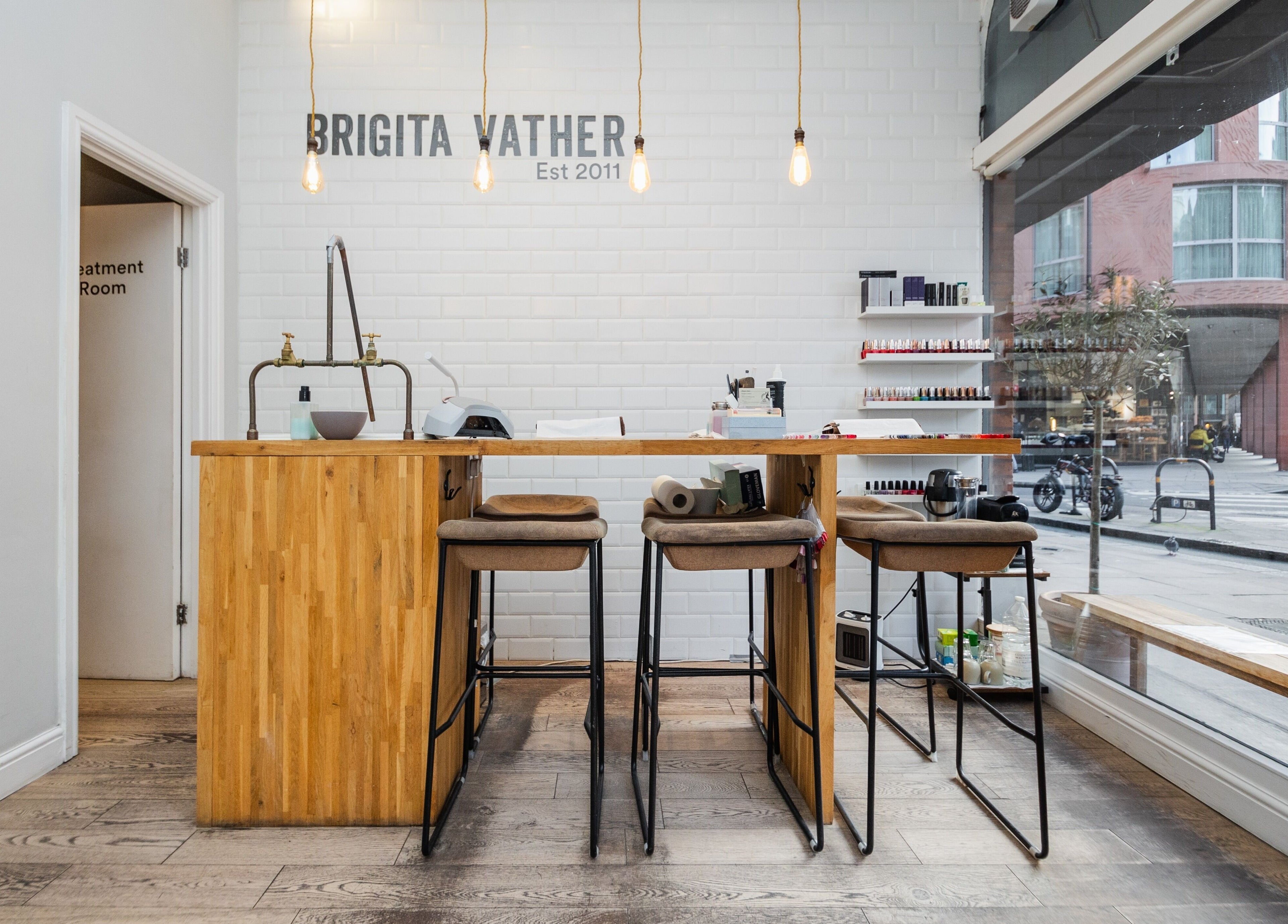 Chic and modern interior of Brigita Vather salon in London, England, GB, featuring stylish bar stools and nail polish display.