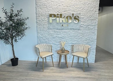Elegant seating area at Piko’s Spa, Sarasota, Florida, US, with chairs and a plant against a textured wall.