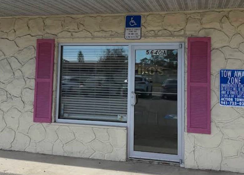 Front entrance of Piko’s Spa in Sarasota, Florida, US with stone exterior and pink shutters.