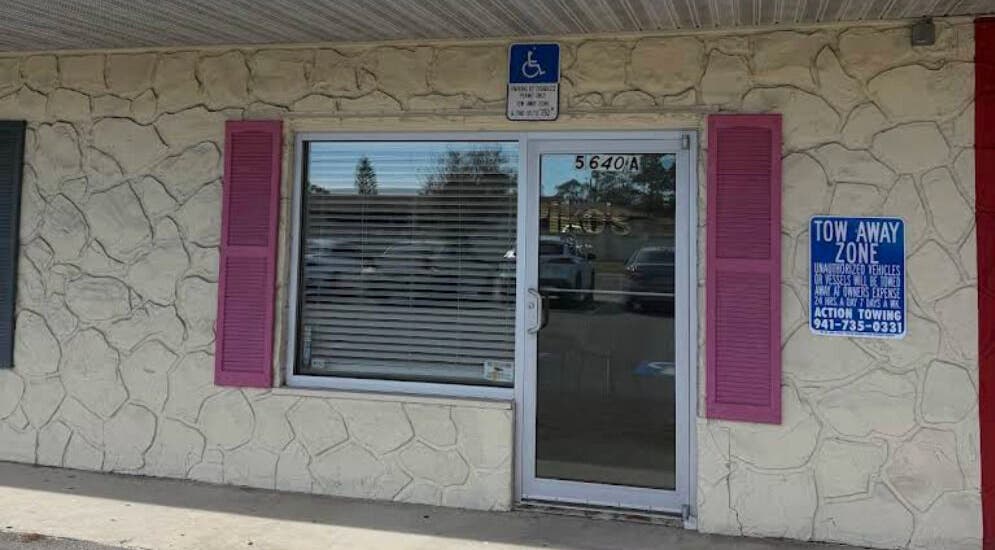 Front entrance of Piko’s Spa in Sarasota, Florida, US with stone exterior and pink shutters.