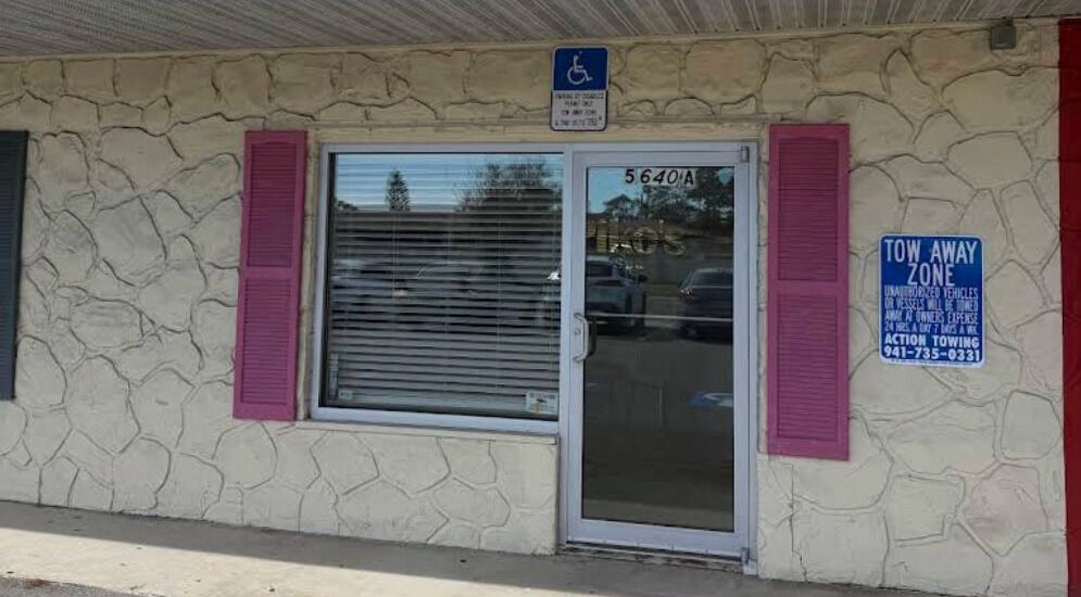 Front entrance of Piko’s Spa in Sarasota, Florida, US with stone exterior and pink shutters.