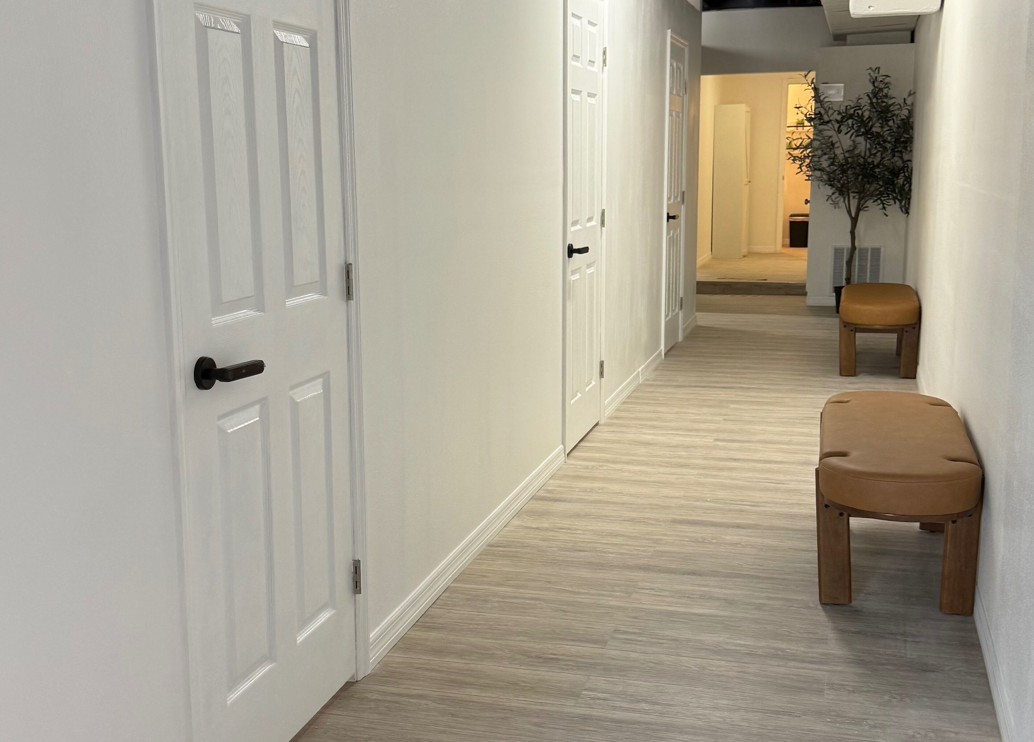 Elegant hallway at Piko’s Spa, Sarasota, Florida, US, featuring minimalist decor with doors and benches.