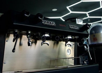 Sleek coffee machine at PLAN B | THE STRAND, Tas-sliema, MT. Modern ambiance with hexagonal lights.