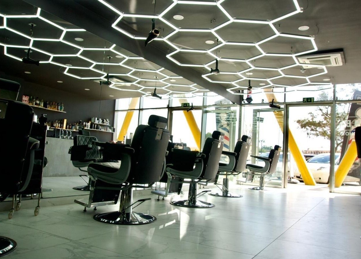 Modern barber chairs at PLAN B | THE STRAND, Tas-sliema, MT. Stylish interior with hexagonal ceiling lights.
