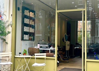Exterior view of SetbyFloss salon, London, England, GB with stylish seating and greenery.