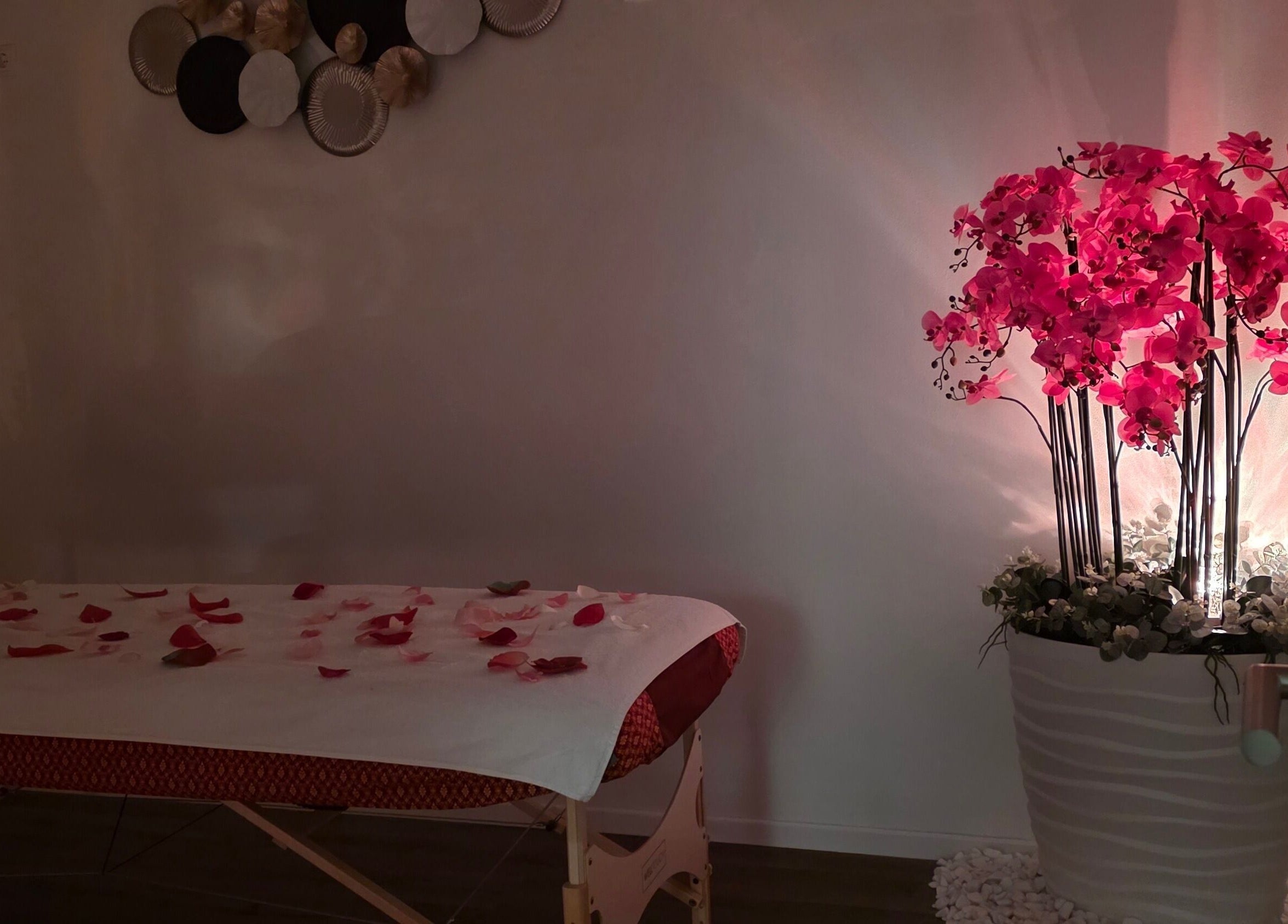 Opustajuća soba u Sawasdee thai massage Labin, Labin, Istarska Županija, HR s crvenim cvijećem i masažnim stolom.